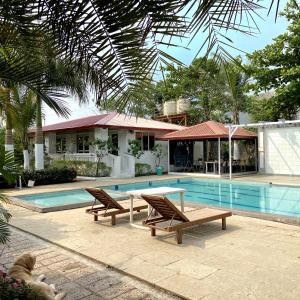a pool with two chairs and a table next to a house at pra tiksha farm in Karjat