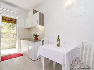 a kitchen with a white table and a white table and chairs at Apartments Matu ko Mljet - One Bedroom Apartment with Balcony and Sea View in Saplunara