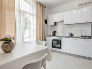 a kitchen with white cabinets and a table with a vase on it at Apartments K & N - One bedroom apartment A2 in Prizba