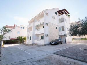 un gran edificio blanco con un coche aparcado en un aparcamiento en Apartment Budimir - Two Bedroom Apartment with Balcony, en Supetar