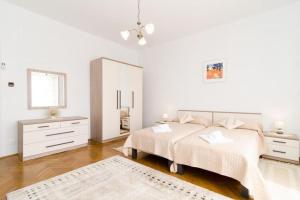 a white bedroom with a bed and a mirror at Holiday Home Patricija-Duplex Three Bedroom Apartment with Balcony and Sea View A6 1 in Dubrovnik