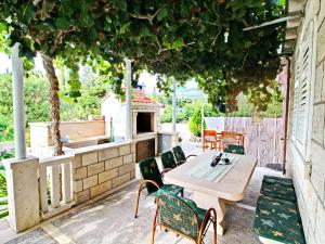 a patio with a table and chairs under a tree at Green Garden House - Four Bedroom House with Private Pool in Žrnovo