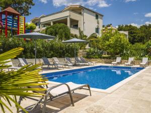 ein Pool mit Stühlen und Sonnenschirmen neben einem Haus in der Unterkunft Villa Dvori Vi kovi-Seven Bedroom Villa with Swimming Pool in Podstrana