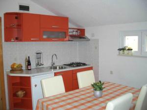 a kitchen with orange cabinets and a table and a sink at Apartment in Bol with balcony in Bol