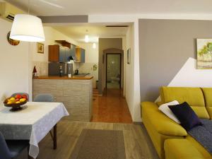 a living room with a yellow couch and a kitchen at Apartment Marita - One Bedroom Apartment with Balcony in Čilipi