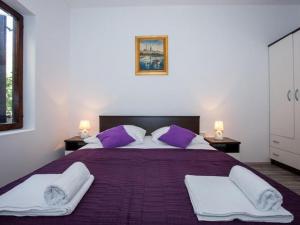 ein Schlafzimmer mit einem großen Bett mit lila und weißen Kissen in der Unterkunft Villa Roza- Two-Bedroom Apartment in Mokošica + 18 Fotos