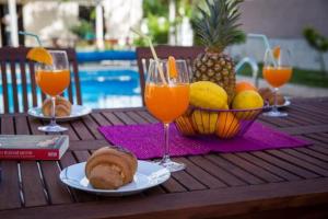 einen Tisch mit Gläsern Orangensaft und einen Obstkorb in der Unterkunft Villa Roza- Two-Bedroom Apartment in Mokošica