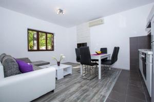 ein Wohnzimmer mit einer weißen Couch und einem Tisch in der Unterkunft Villa Roza- Two-Bedroom Apartment in Mokošica