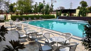 a group of tables and chairs next to a swimming pool at Heena Heritage Resort in Jaipur