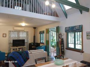 ein Wohnzimmer mit Sofa und Tisch in der Unterkunft Alba the Scots Cottage walk every where in Maleny