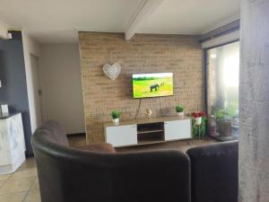 a living room with two chairs and a tv on a brick wall at Boitumelo Bluewater Apartments in Port Elizabeth