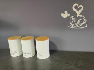 three white cups sitting on a table with a cup of coffee at Boitumelo Bluewater Apartments in Port Elizabeth