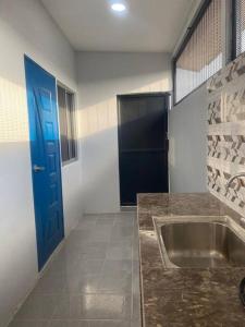 a bathroom with a sink and a blue door at JJ Homestay Terengganu in Marang