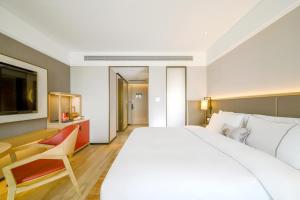 南宁Nanning Vientiane City Convention and Exhibition Center Yicheng Hotel的酒店客房设有一张白色大床和椅子 更多5张照片