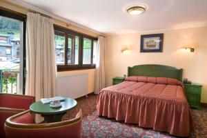 1 dormitorio con cama con colcha roja y mesa en Rutllan & Spa en La Massana