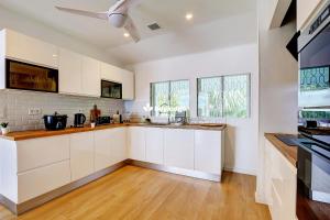 una cucina con armadi bianchi e un ventilatore a soffitto di Villa Vénus - classée 4 étoiles - Piscine et vue mer - Saint-Gilles les Bains a L'Ermitage-Les-Bains