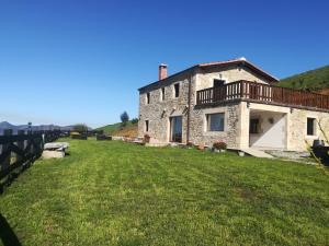 a stone house with a balcony on a green field at Casa Rural Costalisa in Abionzo
