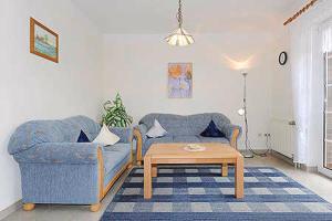 ein Wohnzimmer mit einer blauen Couch und einem Couchtisch in der Unterkunft Ferienwohnungen Haus Taddigshus in Bensersiel