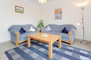 ein Wohnzimmer mit 2 blauen Sofas und einem Couchtisch in der Unterkunft Ferienwohnungen Haus Taddigshus in Bensersiel