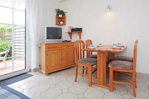 ein Esszimmer mit Tisch und Stühlen und einem Fernseher in der Unterkunft Ferienwohnungen Haus Taddigshus in Bensersiel