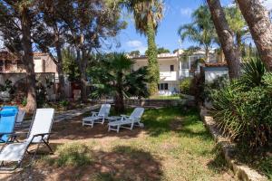 a yard with two lawn chairs and palm trees at Casa cancello a mare in Santa Flavia