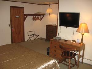 a bedroom with a bed and a dresser with a television at Big Bears Lodge in West Dover