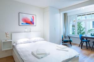 ein weißes Schlafzimmer mit einem Bett und einem Schreibtisch in der Unterkunft HITrental Riesbach Apartments in Zürich