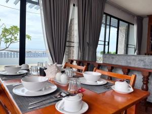 a wooden table with plates and cups on top of it at Penthouse ศรีราชา วิวทะเล ATHOME SRIRACHA in Ban Rai Kluai