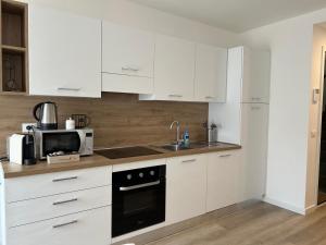 una cucina con mobili bianchi, un lavello e un microonde di Fanzago Trilo Home a Clusone