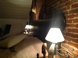 a bedroom with a brick wall and a bed with two lamps at Vakantiewoning Ijzerrust in Roesbrugge-Haringe