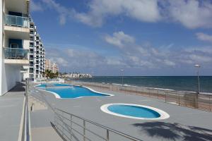 zwei Swimmingpools am Strand neben einem Gebäude in der Unterkunft Gran Lugar -Mar Azul in La Manga del Mar Menor