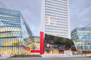 サン・ドニにあるH4 Hotel Wyndham Paris Pleyel Resortの看板が目の前にある大きなガラス張りの建物