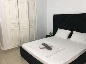 ein Bett mit schwarzem Kopfteil und einem Telefon darauf in der Unterkunft Appartement meublé 3 chambres Cité Mixta in Grand Médina