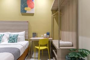 1 dormitorio con 1 cama y escritorio con silla amarilla en Mono Coliving Ngagel, Surabaya, en Menurpumpungan