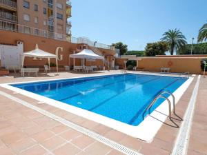 a swimming pool with tables and umbrellas next to a building at Apartamento Terraza Mar in Malgrat de Mar