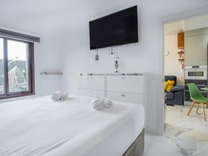Una habitación blanca con una cama y un televisor en la pared. en ProApartment Del Mar B82 Modern 1BD apartment with amazing terrace and pool!, en Costa del Silencio
