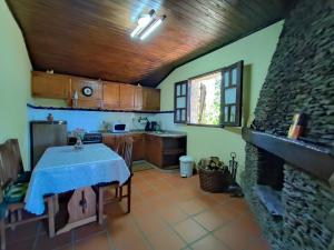 cocina con mesa y chimenea de piedra en Casa da Fonte - Branda da Aveleira, en Melgaço