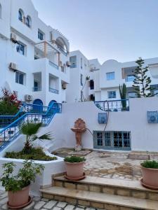 ein weißes Gebäude mit Topfpflanzen davor in der Unterkunft Appartement Hammamet Nord in Hammamet Nord