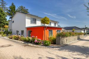 a white and orange house with flowers in front of it at Ferienhaus 6 Schlafzimmer mit Sauna UnserUsedom Ostseebad Koserow Insel Usedom in Ostseebad Koserow