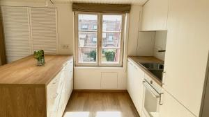 a kitchen with white cabinets and a large window at City Center Appartment in Vilnius +1 photo