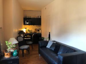 Una sala de estar con un sofá negro y una cocina. en Le petit matelot, en Paimpol