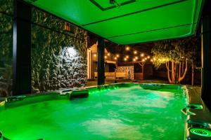 a jacuzzi tub in a room with green lighting at Farm House at Mochdre Cottages in Conwy