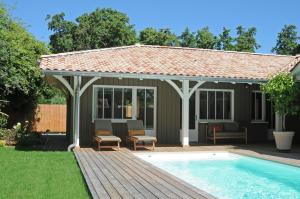 a gazebo with a deck next to a pool at La villa aux oiseaux in Andernos-les-Bains
