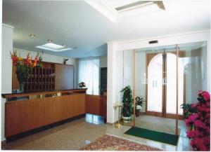 a lobby with a reception desk and flowers in a building at Hotel 2000 in Fabriano