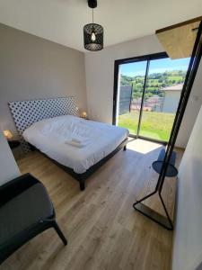 a bedroom with a bed and a large window at Rez-de-jardin de Maison avec spa et borne d'arcade in Aurillac