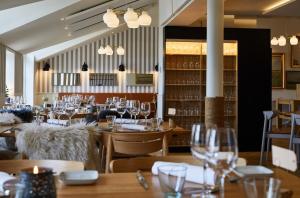a restaurant with wooden tables and chairs and wine glasses at Gl. Avernæs Sinatur Hotel & Konference in Ebberup