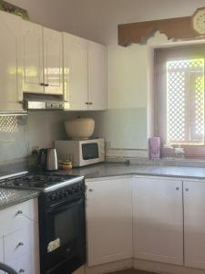 Villa Domina Coral Bay في شرم الشيخ: مطبخ بدولاب بيضاء وفرن توب موقد اسود +15 صورة