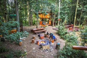 a group of people sitting around a fire in the woods at Treehous Sněžník s wellness in Dolní Morava
