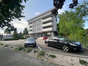 APARTMAN DBR -Dobrinja Sarajevo-FREE GARAGE في سراييفو: سيارتان متوقفتان في موقف السيارات أمام مبنى