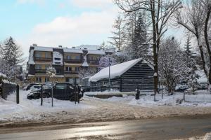 a building with snow on the ground next to a street at Mountain Corner Apartment in Zakopane by Noclegi Renters in Zakopane